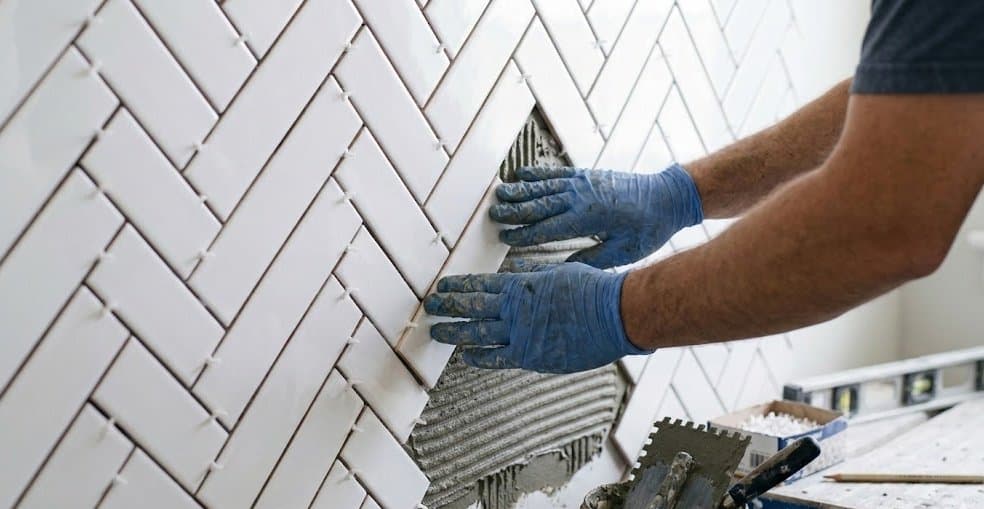 Fliesenleger verlegt Fliesen im Fischgrätmuster